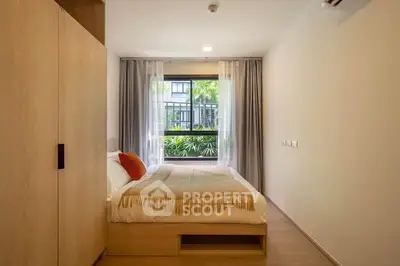 Modern bedroom with large window and stylish decor in a cozy apartment.