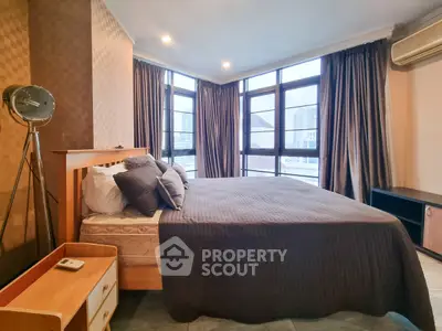 Spacious bedroom with large windows and city view, featuring modern decor and ample natural light.