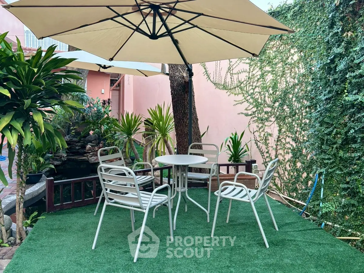 Charming garden patio with outdoor seating and lush greenery, perfect for relaxation and entertaining.