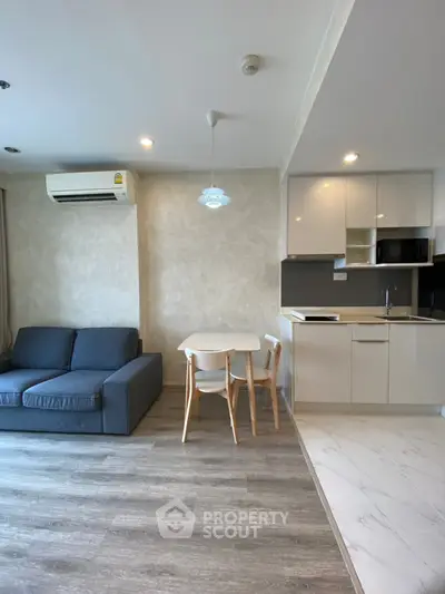 Modern living room with open kitchen, featuring sleek furniture and contemporary design.