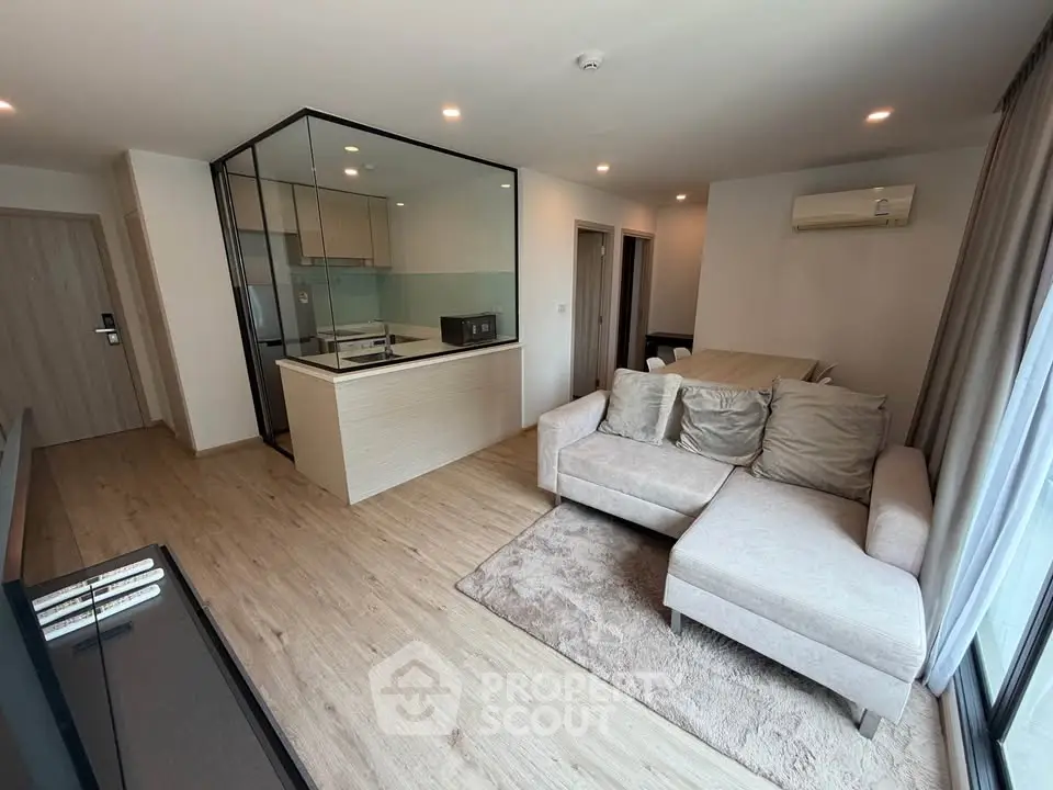 Modern living room with open kitchen and cozy seating area in a stylish apartment.