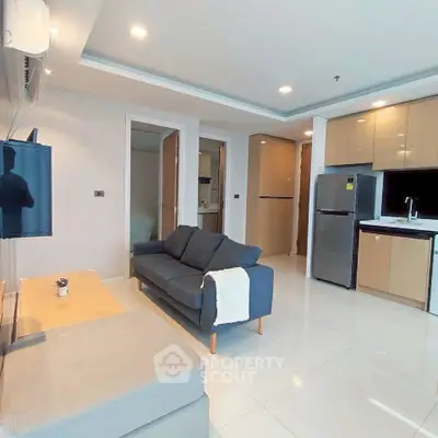 Modern living room with sleek kitchen, featuring stylish furniture and contemporary design.