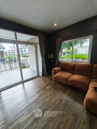 Spacious living room with large windows and cozy sofa, featuring a view of the garden.