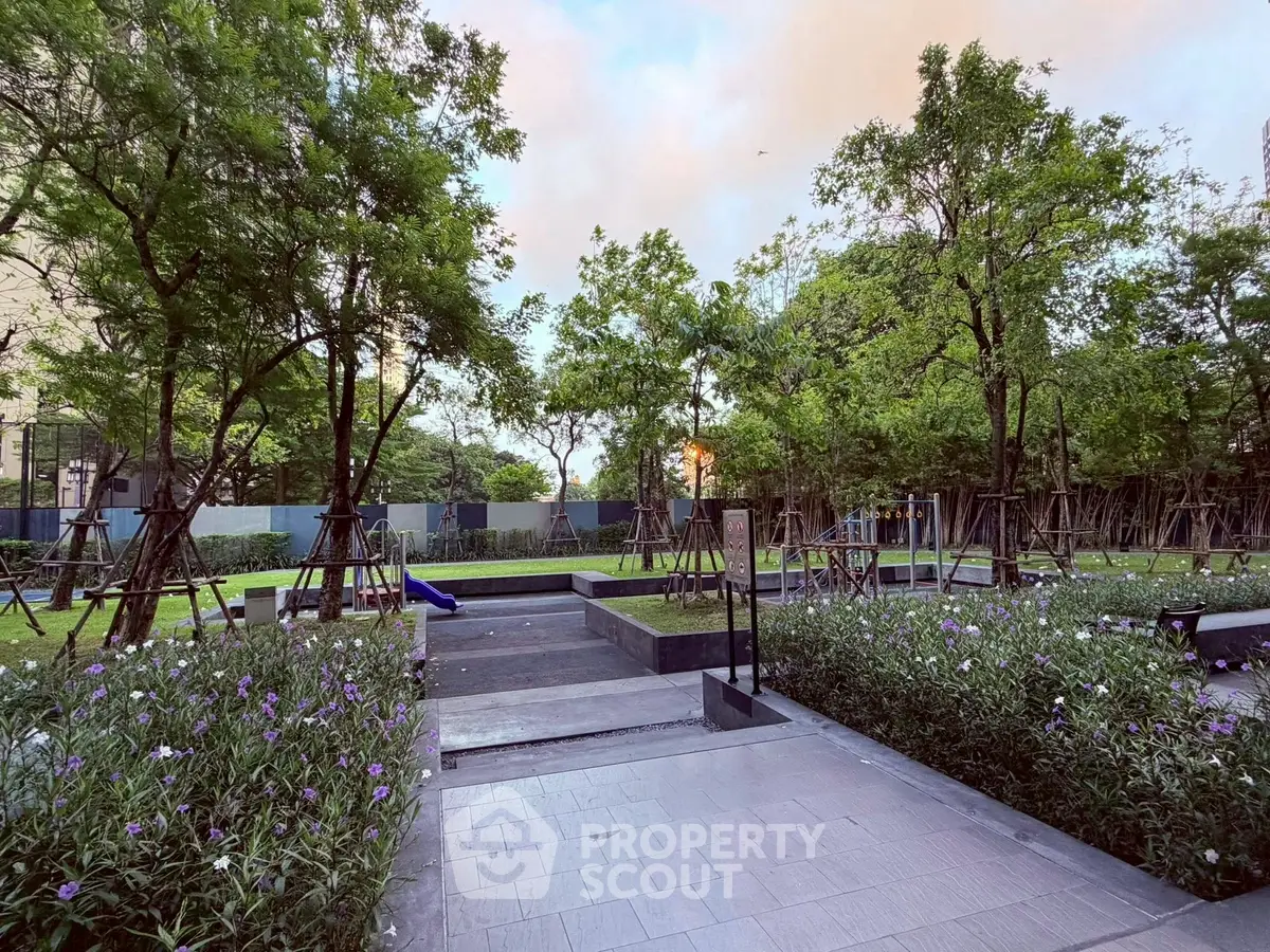 Serene garden area with lush greenery and paved walkways in a modern residential complex.