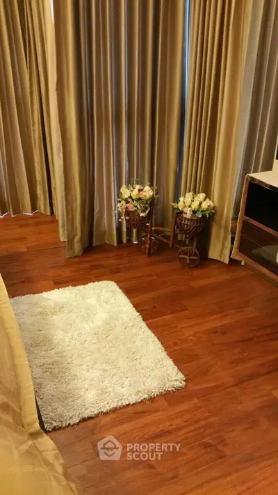 Cozy bedroom corner with wooden flooring and elegant curtains