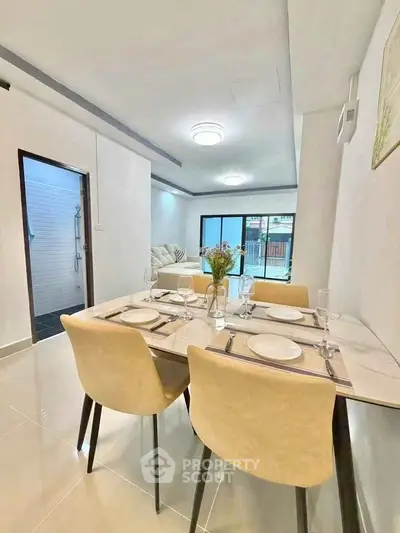 Modern dining area with elegant table setting and view into cozy living room