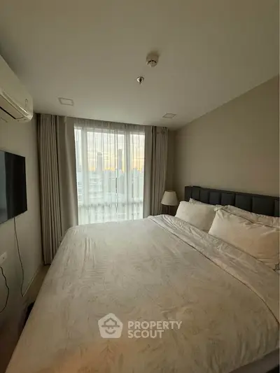 Cozy bedroom with large window and modern decor in a high-rise apartment.