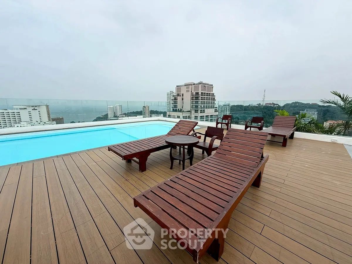 Luxurious rooftop pool area with stunning city views and wooden lounge chairs.
