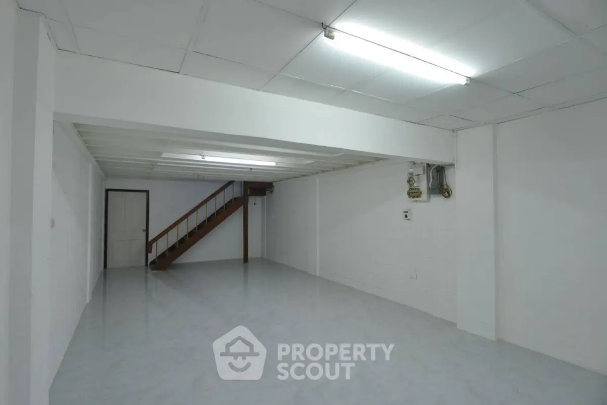 Spacious basement area with staircase and bright lighting, ideal for storage or creative use.