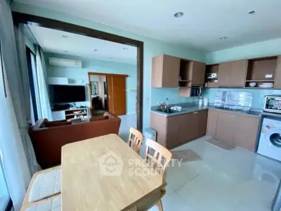 Modern open-layout kitchen and living room with sleek appliances and cozy seating area.