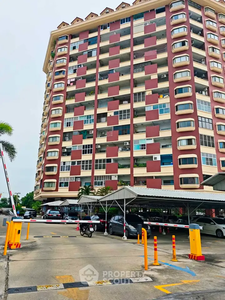 Modern high-rise building with parking area and security features in urban setting.