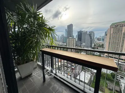 Stunning cityscape view from a modern balcony with lush greenery and sleek railing.