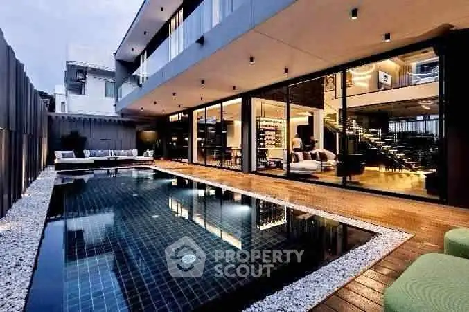 Luxurious modern home with sleek pool and stylish outdoor seating area, perfect for entertaining.