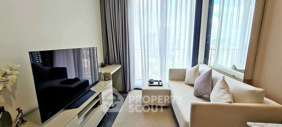 Modern living room with large TV, cozy sofa, and floor-to-ceiling windows offering city views.
