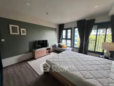 Spacious bedroom with modern decor and large windows offering natural light.