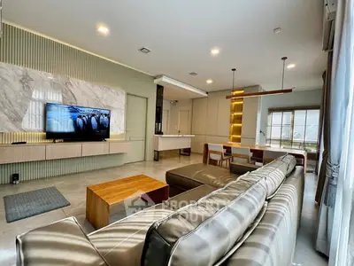 Modern living room with sleek design, featuring a large TV, stylish furniture, and open layout.