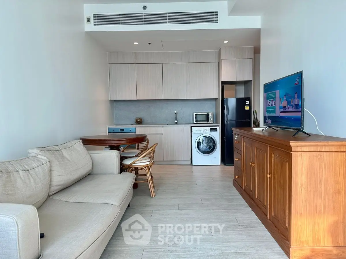 Modern living room with integrated kitchen and appliances, featuring a cozy sofa and wooden furniture.