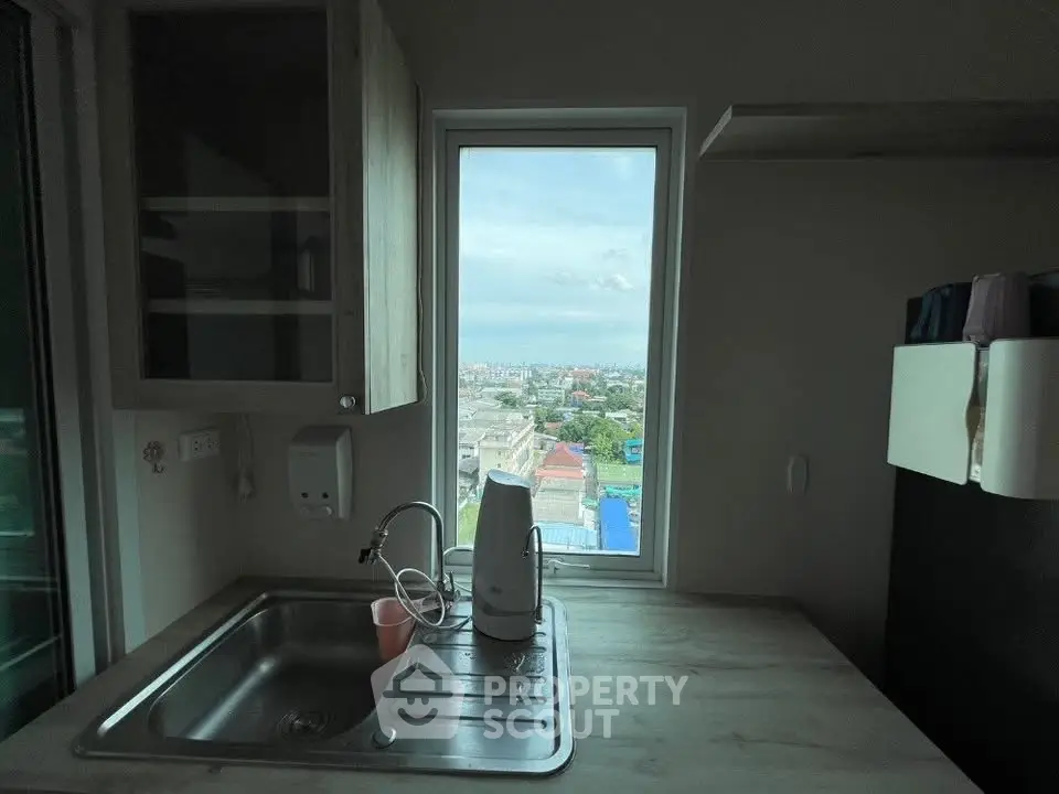Compact kitchen with a stunning city view from the window, featuring modern cabinetry and a sleek sink.