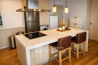 Modern kitchen with island, stainless steel appliances, and stylish lighting in a contemporary apartment.