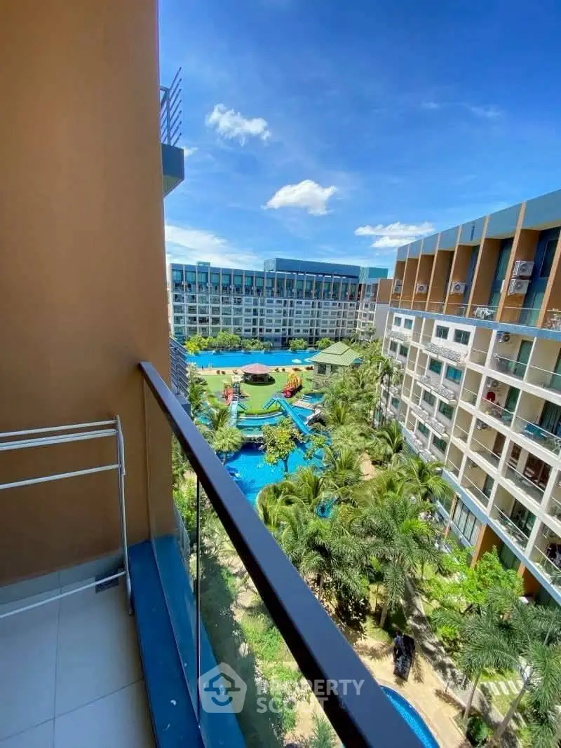 Stunning balcony view of modern apartment complex with lush gardens and inviting pool area.