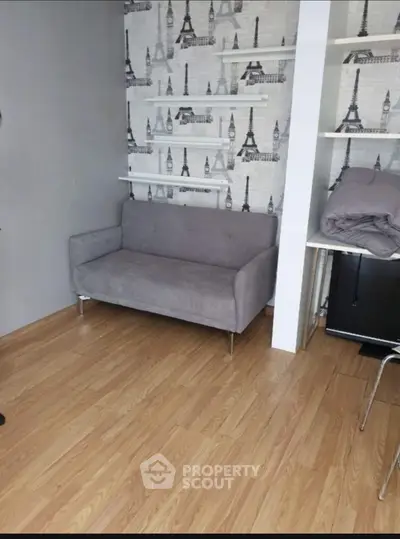 Cozy small living room with stylish wallpaper and modern gray sofa.