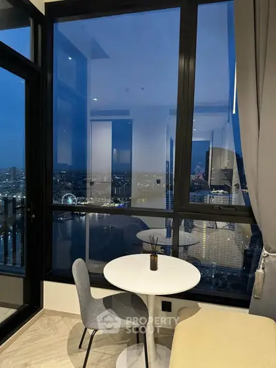 Stunning city view from modern high-rise apartment with cozy seating area.