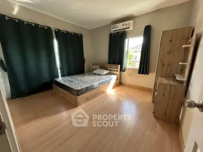 Spacious bedroom with wooden flooring and large windows for natural light