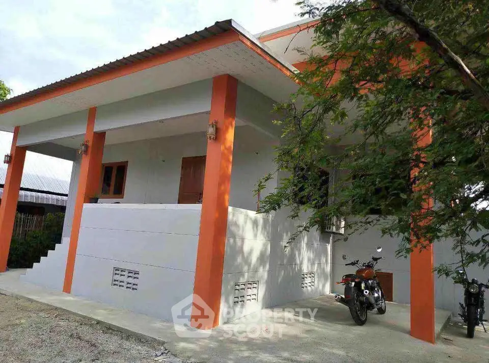 Charming single-story home with vibrant orange accents and spacious porch.