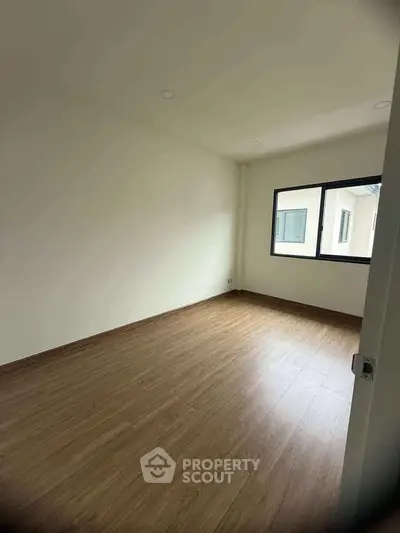 Spacious empty room with wooden flooring and large window