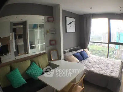 Modern studio apartment with cozy bed and city view, featuring stylish decor and ample natural light.
