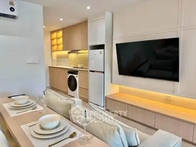Modern open-plan living room with kitchen, featuring sleek appliances and elegant dining setup.