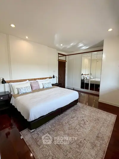 Spacious bedroom with elegant decor and large mirrored wardrobe
