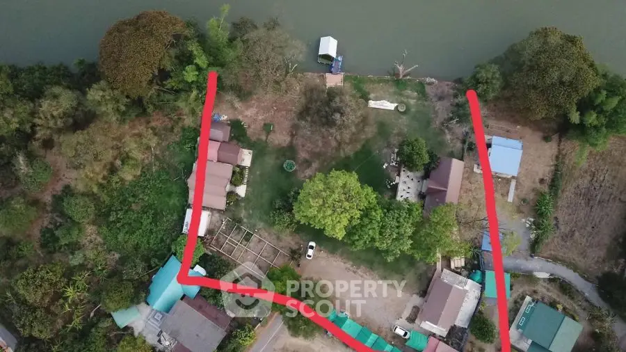 Aerial view of riverside property with lush greenery and multiple buildings.