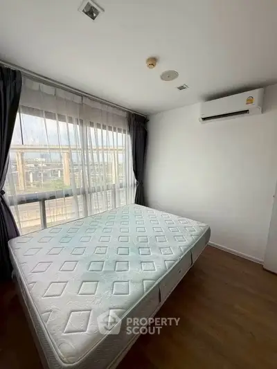 Spacious bedroom with large window and air conditioning, featuring a comfortable mattress and elegant curtains.