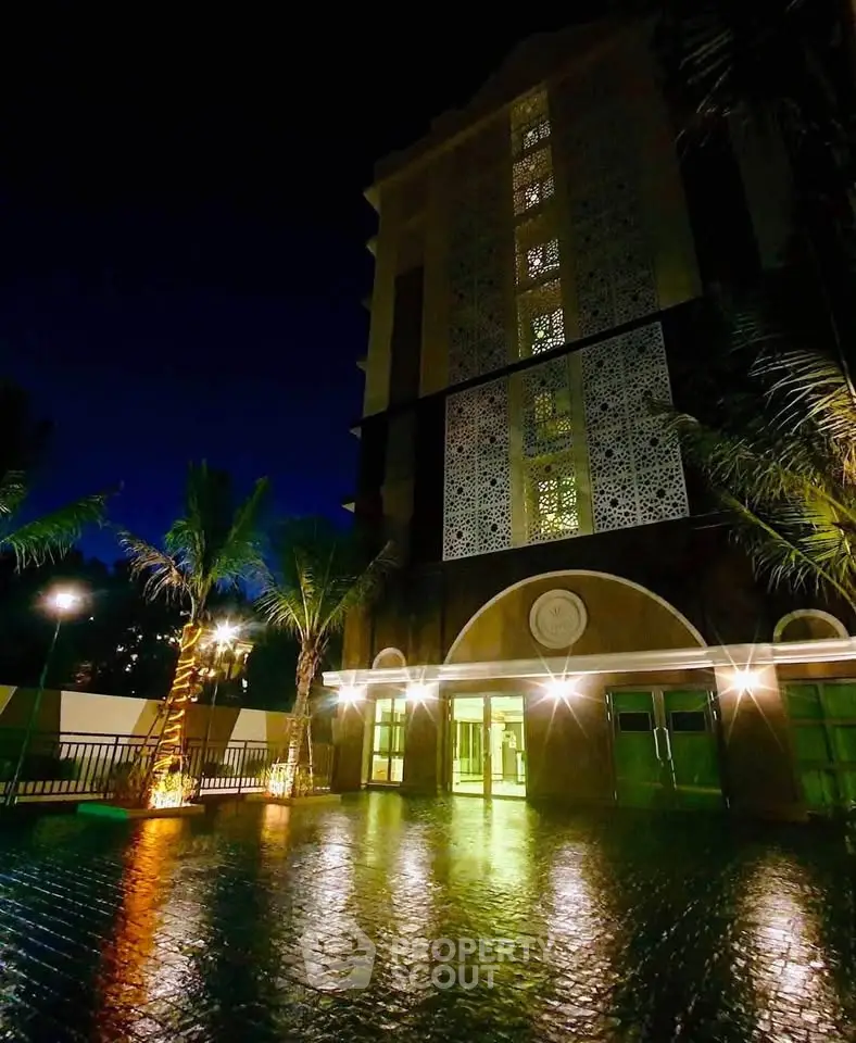 Stunning night view of a modern building entrance with elegant lighting and palm trees.
