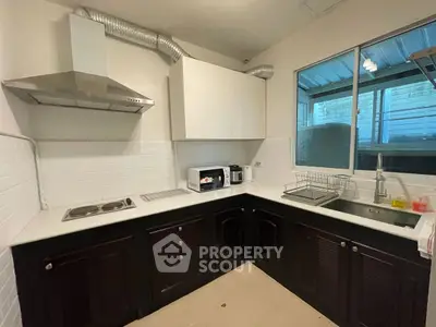 Modern kitchen with dark cabinets, stainless steel appliances, and large window for natural light.
