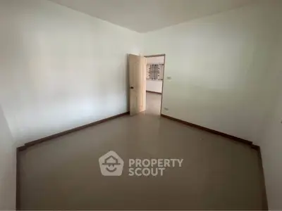 Spacious empty room with glossy tiled floor and open door, ready for customization.