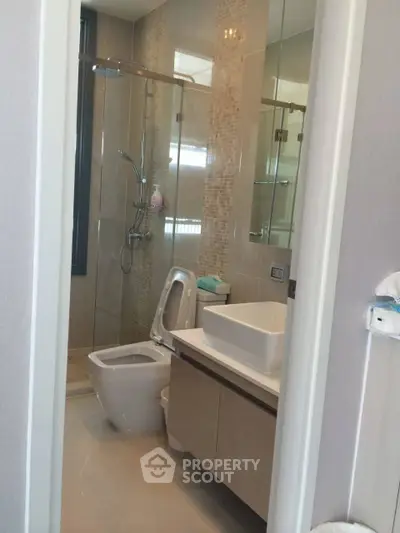 Modern bathroom with sleek fixtures and glass shower enclosure in a stylish apartment.