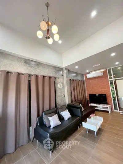 Modern living room with stylish decor, featuring black sofas, elegant lighting, and a sleek entertainment setup.