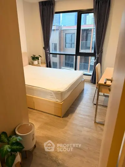 Cozy bedroom with large window and modern furnishings in urban apartment