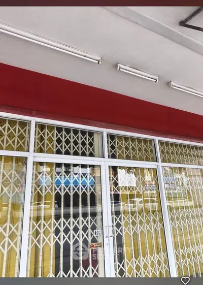 Commercial property exterior with secure metal gates and red awning.