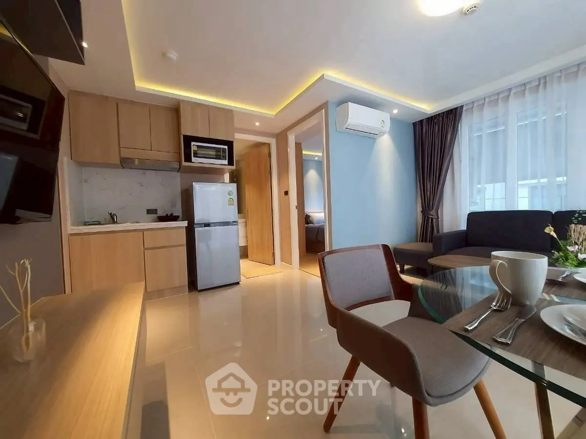 Modern open-layout living room with kitchen, featuring sleek furniture and natural light.