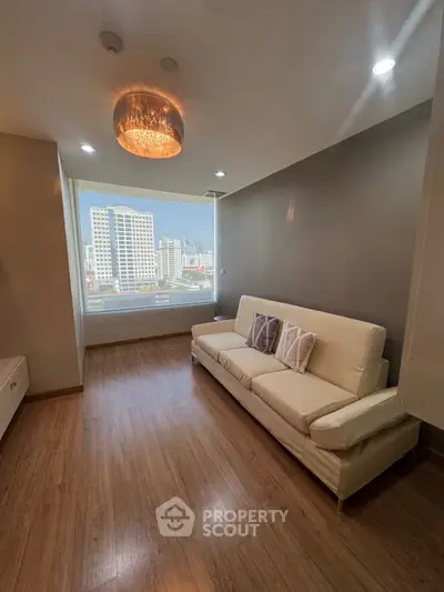 Modern living room with city view, featuring sleek wooden flooring and elegant lighting.