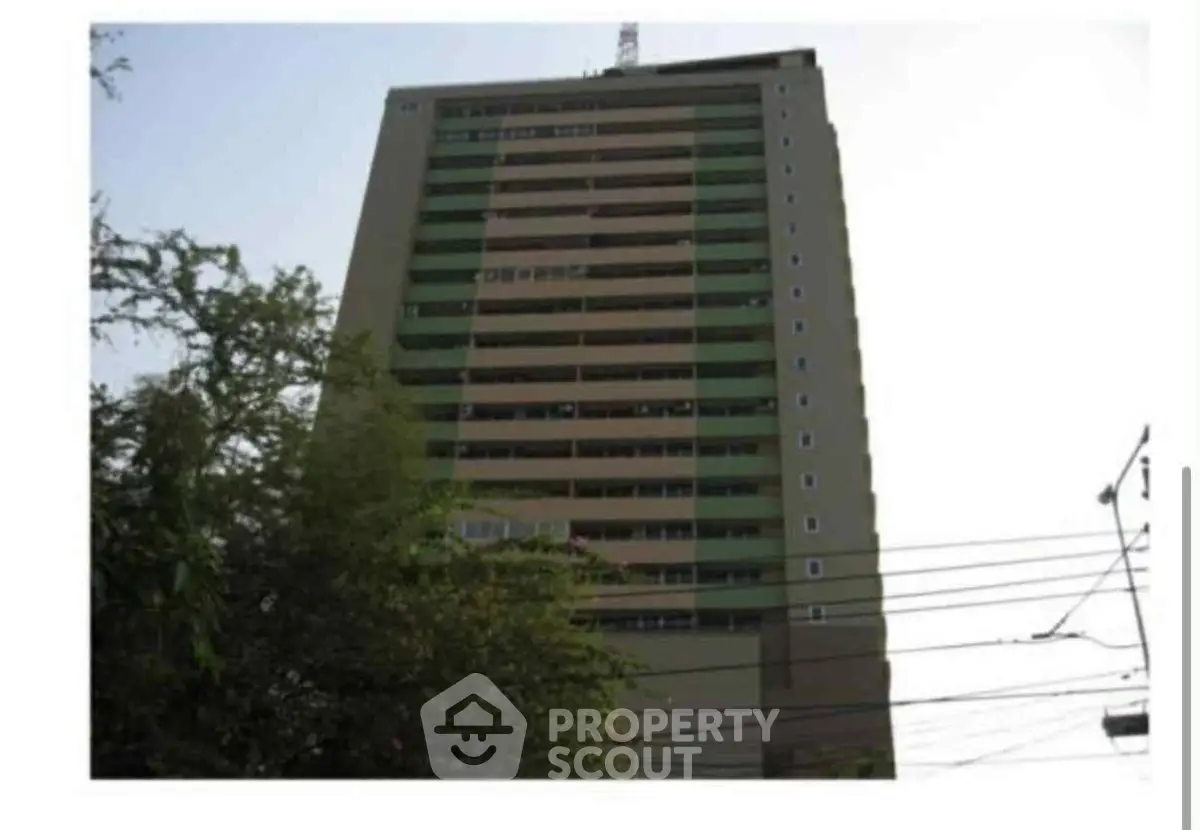 High-rise building exterior with lush greenery and clear sky view.