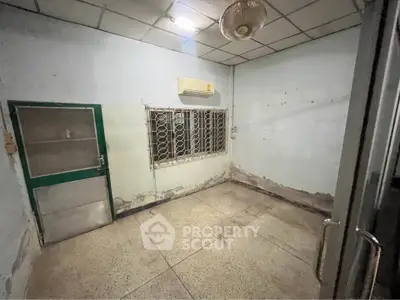 Spacious room with air conditioning and metal window grills, ideal for renovation.