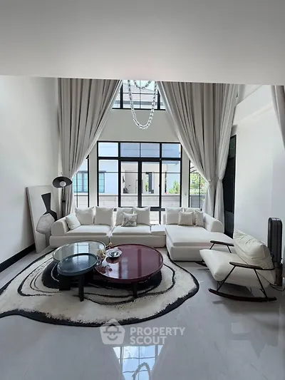 Luxurious living room with high ceilings, elegant decor, and large windows offering abundant natural light.