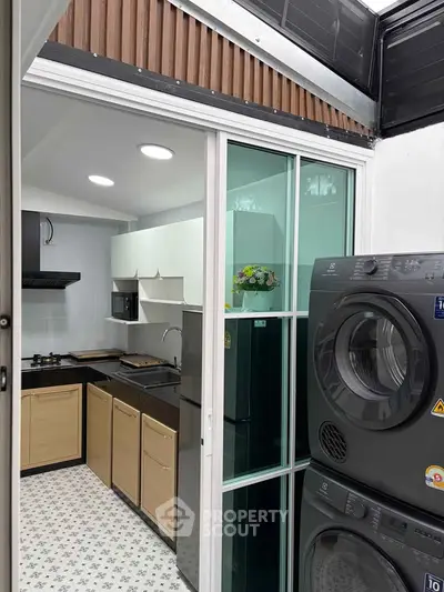 Modern kitchen with sleek appliances and stylish design, featuring a washing machine and dryer stack.