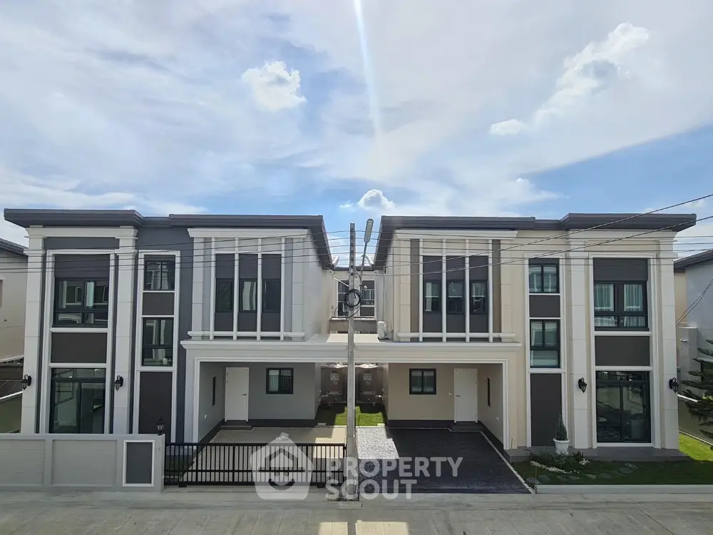 Modern duplex homes with sleek design and spacious driveways under a clear blue sky.