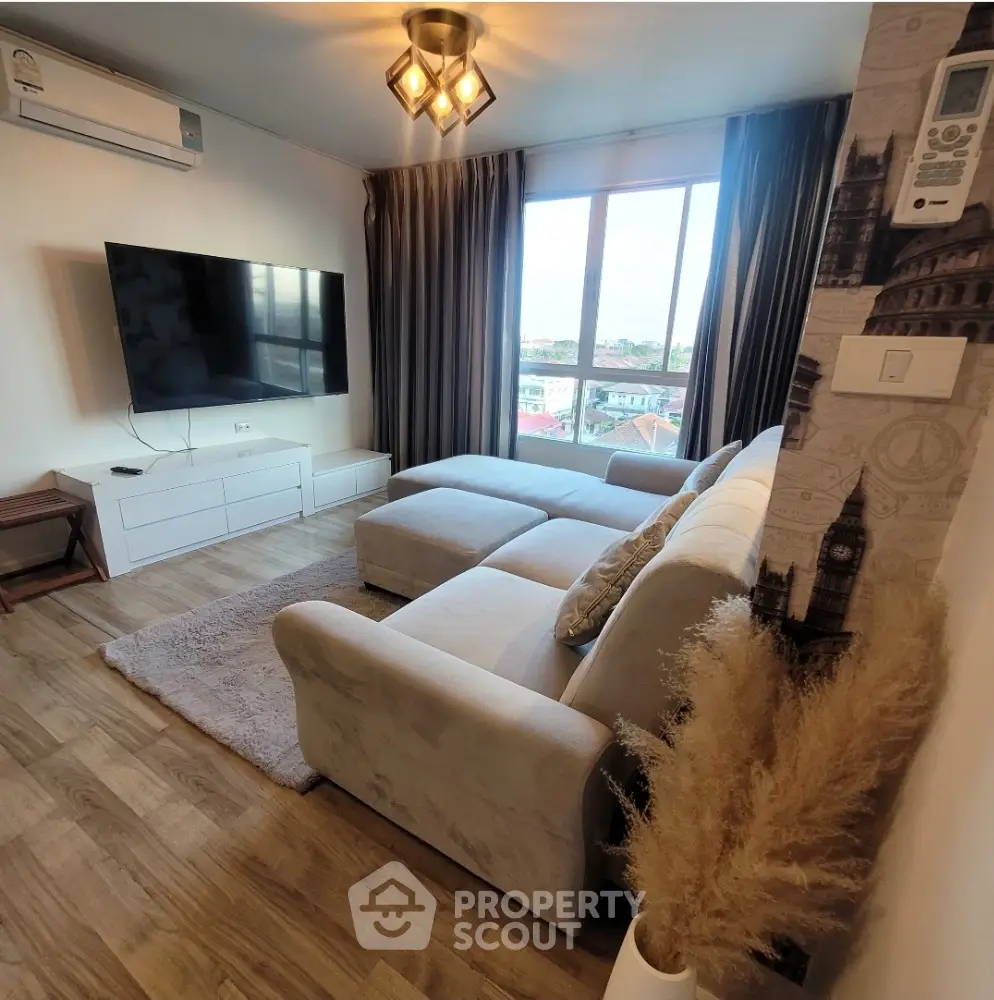 Modern living room with large TV, cozy sofa, and city view window.