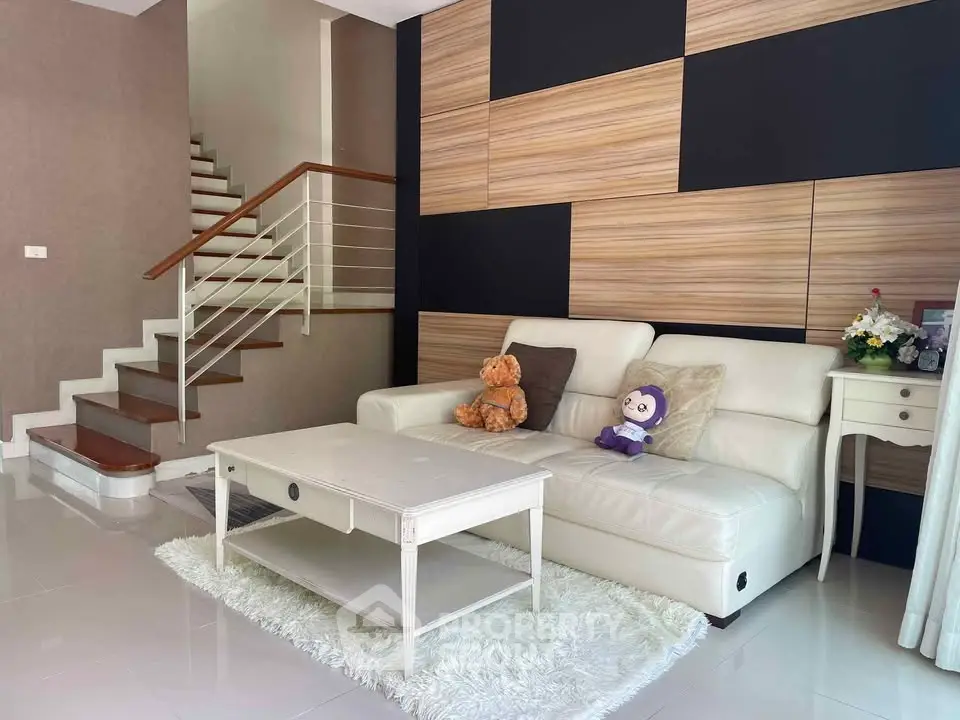 Stylish living room with modern staircase and cozy seating area.